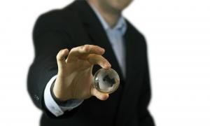 Homme en costume tenant entre ses doigts une bille en forme de mappemonde
